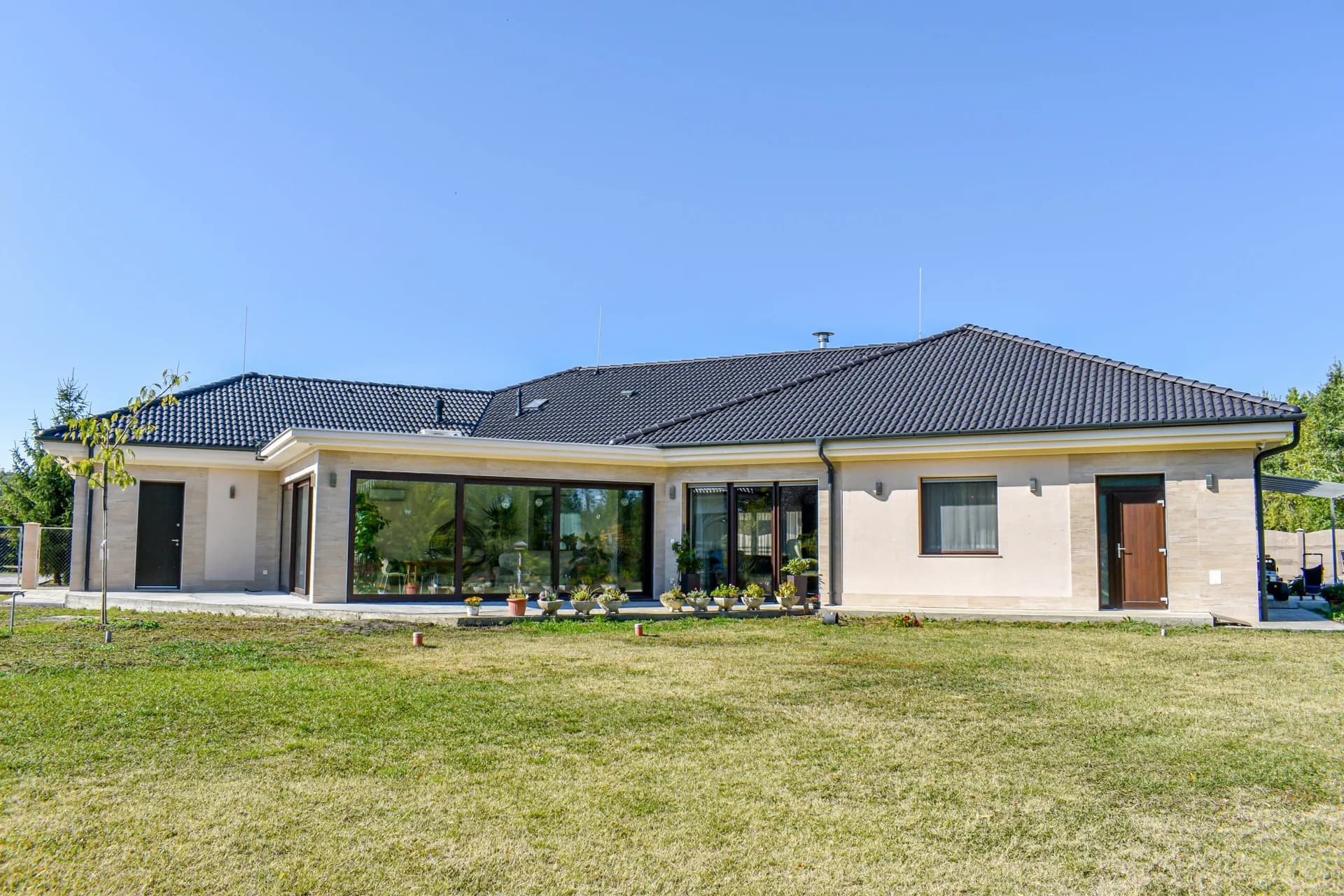 Földszintes családi ház panorámaüvegezéssel és füves kerttel